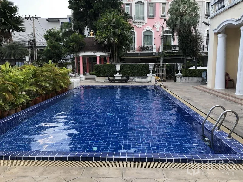 联排别墅 出租在Wang Thonglang, Bangkok - 社区室外公共泳池，蓝色马赛克池面，配金属扶梯与棕榈景观。