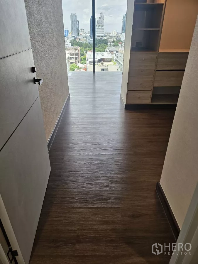 公寓 出租在Watthana, Bangkok - 入口走廊深色木地板，通向落地窗与城市天际线景观。