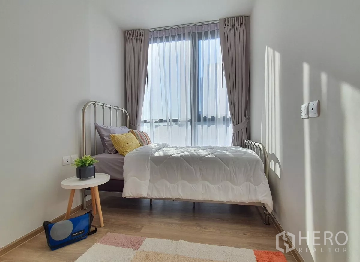Condominium for rent in Khlong Toei, Bangkok - Second bedroom with single bed, large windows and side table.