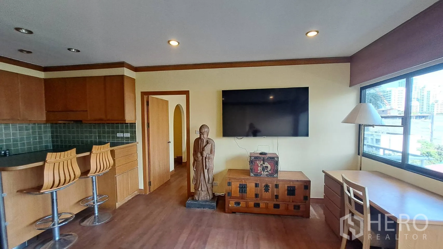 Condominium for rent in Khlong Toei, Bangkok - Open-plan living with breakfast bar, large TV, and study desk.