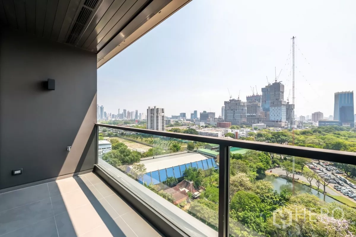 公寓 出租或出售在Pathum Wan, Bangkok - 覆盖式阳台，玻璃栏杆，远眺公园与天际线。