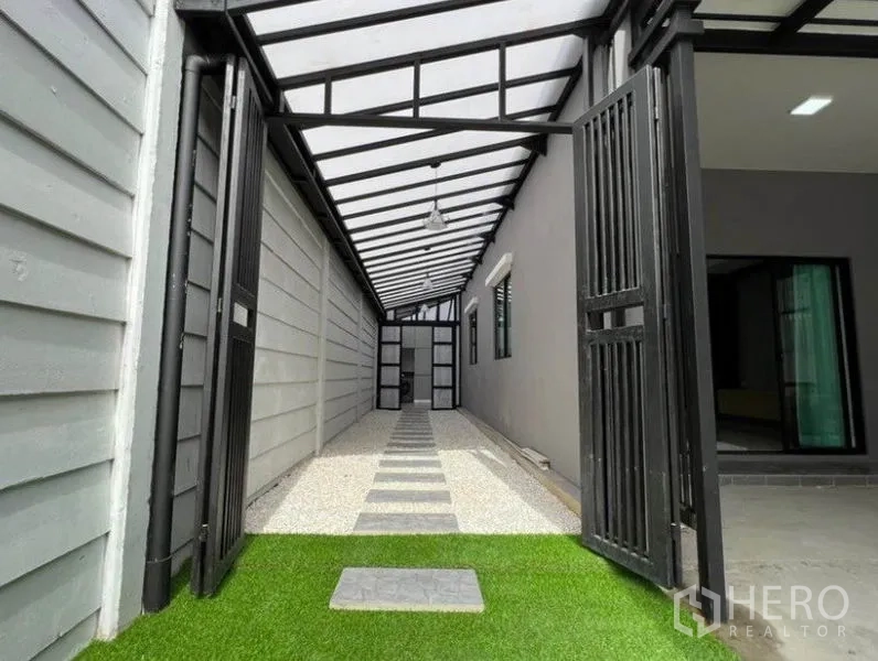 联排别墅 出租在Wang Thonglang, Bangkok - 带顶侧廊，钢结构屋顶、金属门与人造草坪。