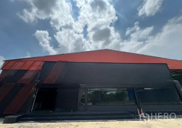 Showroom for rent in Mueang Samut Prakan, Samut Prakan - Modern black-and-red showroom facade with large glass windows under blue sky