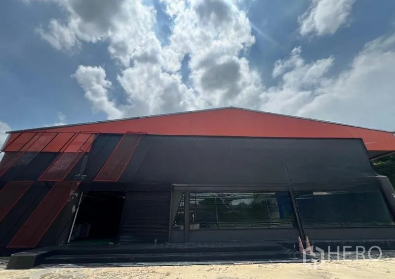 Showroom for rent in Mueang Samut Prakan, Samut Prakan - Modern black-and-red showroom facade with large glass windows under blue sky