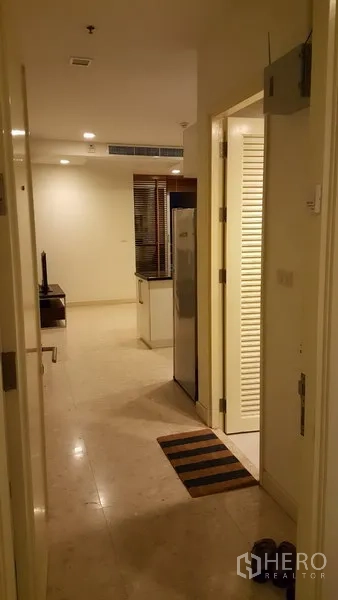 Condominium for rent in Khlong Toei, Bangkok - Entry hallway with stone flooring leading toward the kitchen and living area.