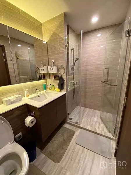 Condominium for rent in Phra Khanong, Bangkok - Contemporary bathroom with glass-enclosed shower, vanity and tiled finishes.