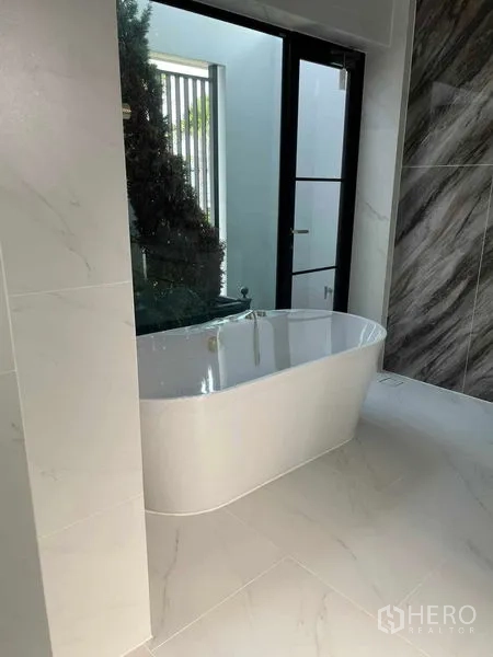 Detached House for sale in Saphan Sung, Bangkok - Luxurious bathroom featuring a freestanding bathtub beside floor‑to‑ceiling window.