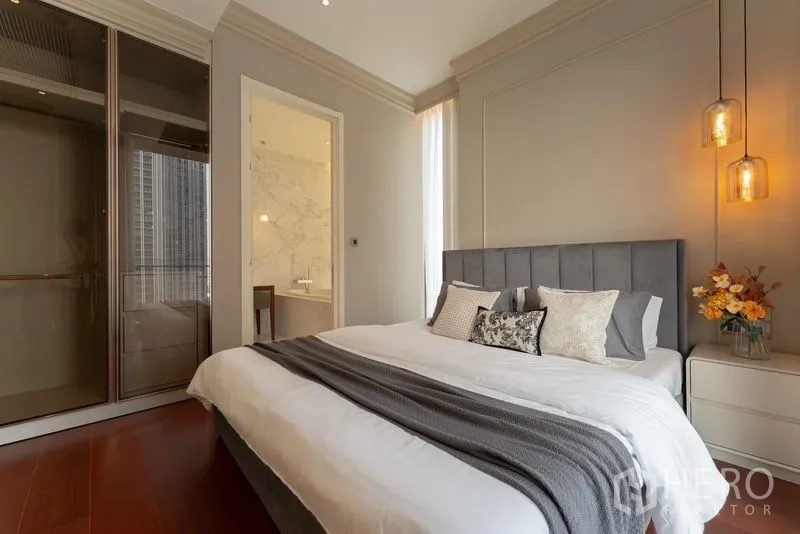 Condominium for rent in Watthana, Bangkok - Master bedroom showing pendant lights, upholstered headboard and door to the marble ensuite bathroom.