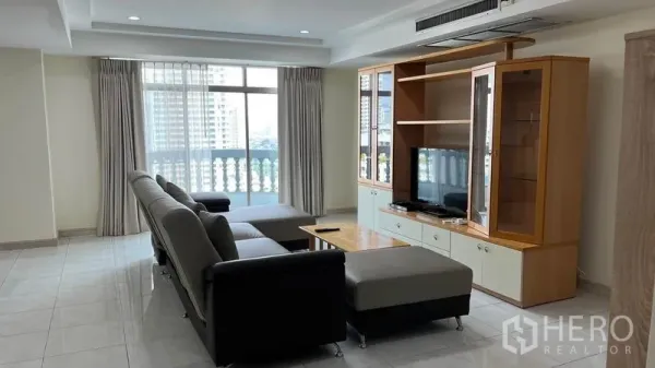 Condominium for rent in Watthana, Bangkok - Bright living room with L-shaped sofa, TV cabinet, balcony and city view in a Watthana condo.