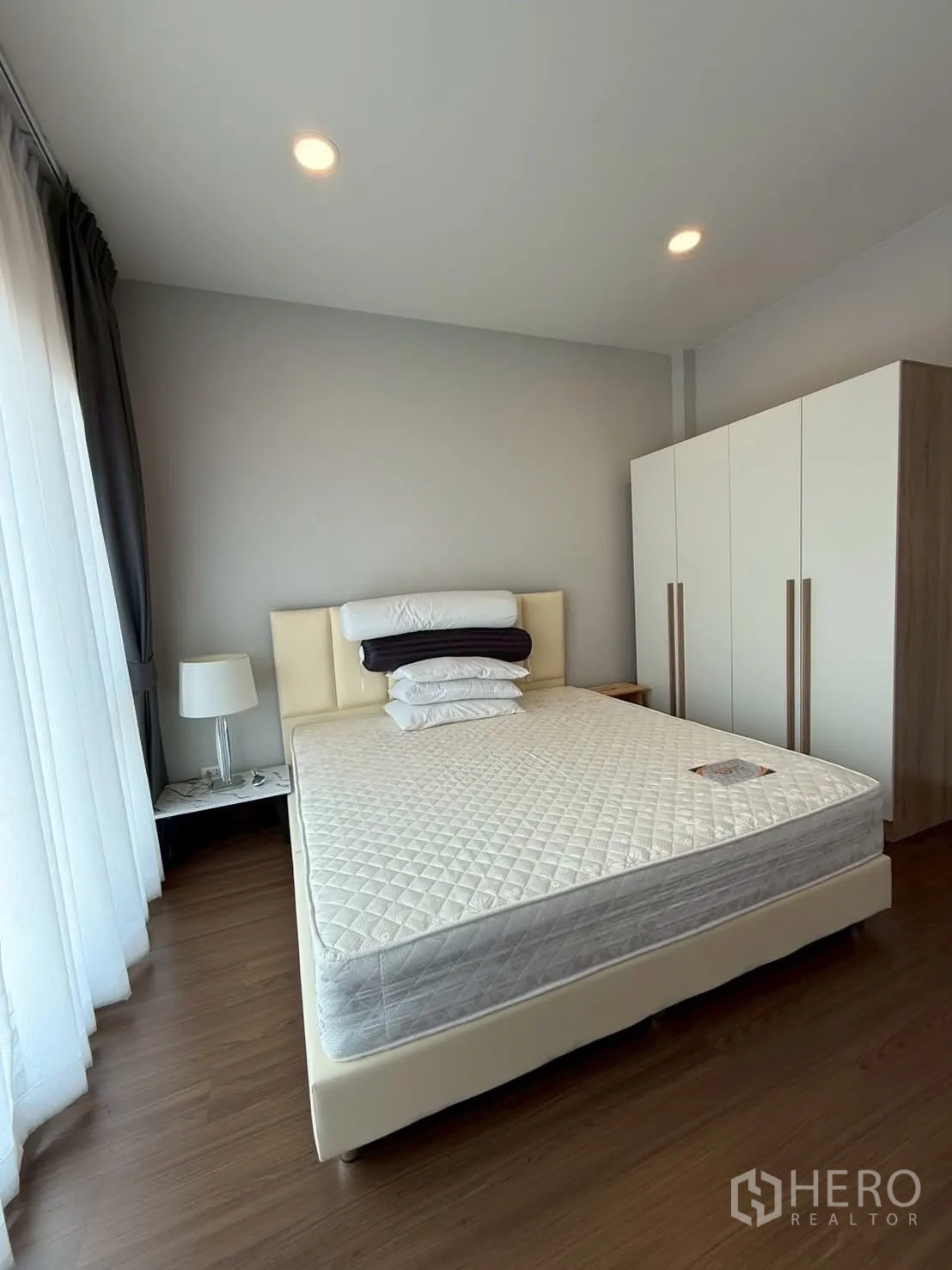 Townhouse for rent - Bedroom with cream bedframe, wardrobe and sheer curtains.