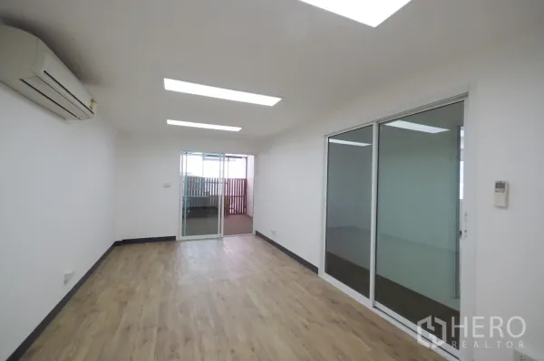 Office Space for rent in Khlong Toei, Bangkok - Long office room with air conditioning and sliding glass partitions opening to a balcony.