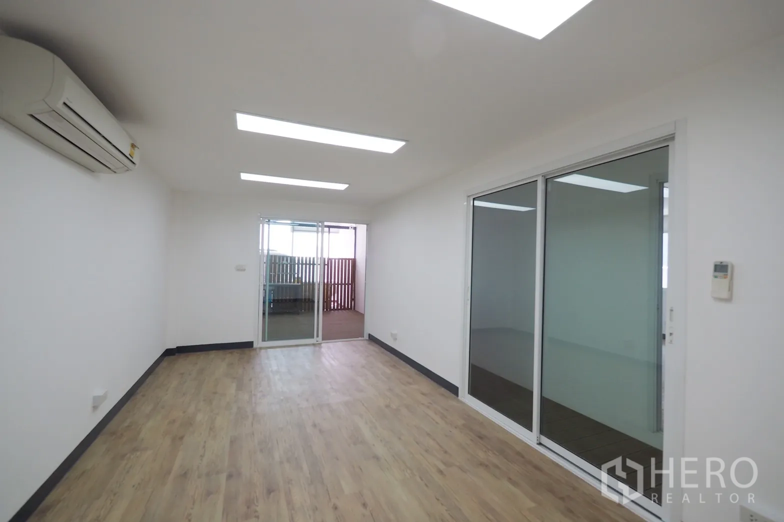 Office Space for rent in Khlong Toei, Bangkok - Long office room with air conditioning and sliding glass partitions opening to a balcony.