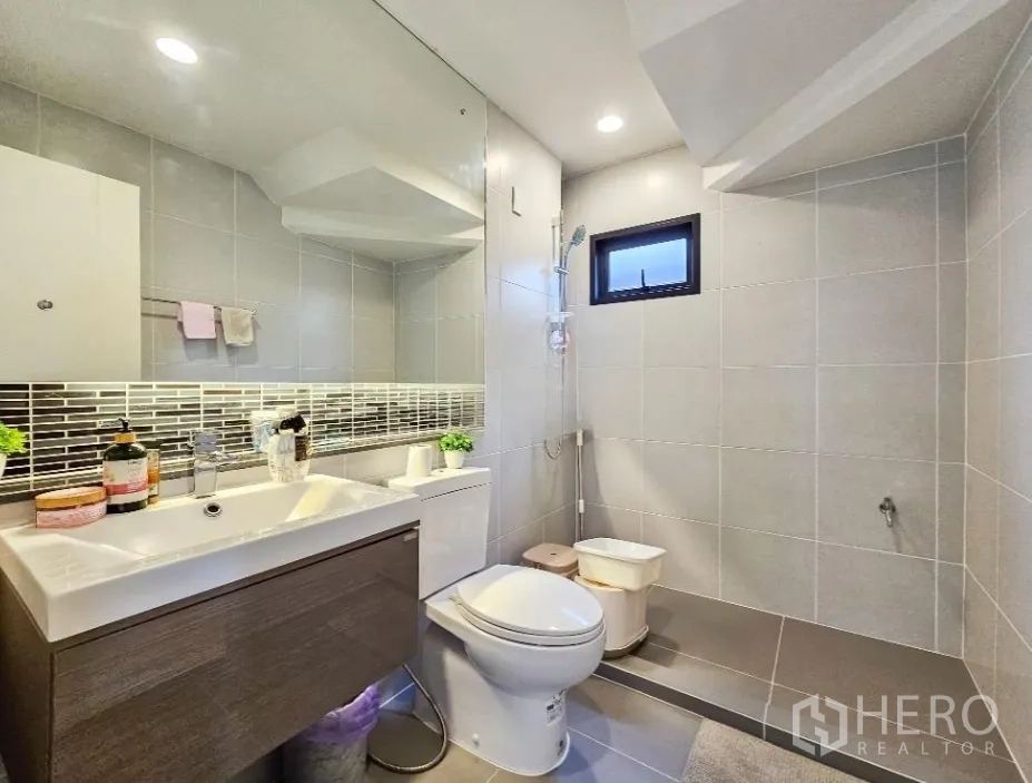 Detached House for sale in Lam Luk Ka, Pathum Thani - Modern bathroom with vanity, toilet and walk-in shower with a small window.