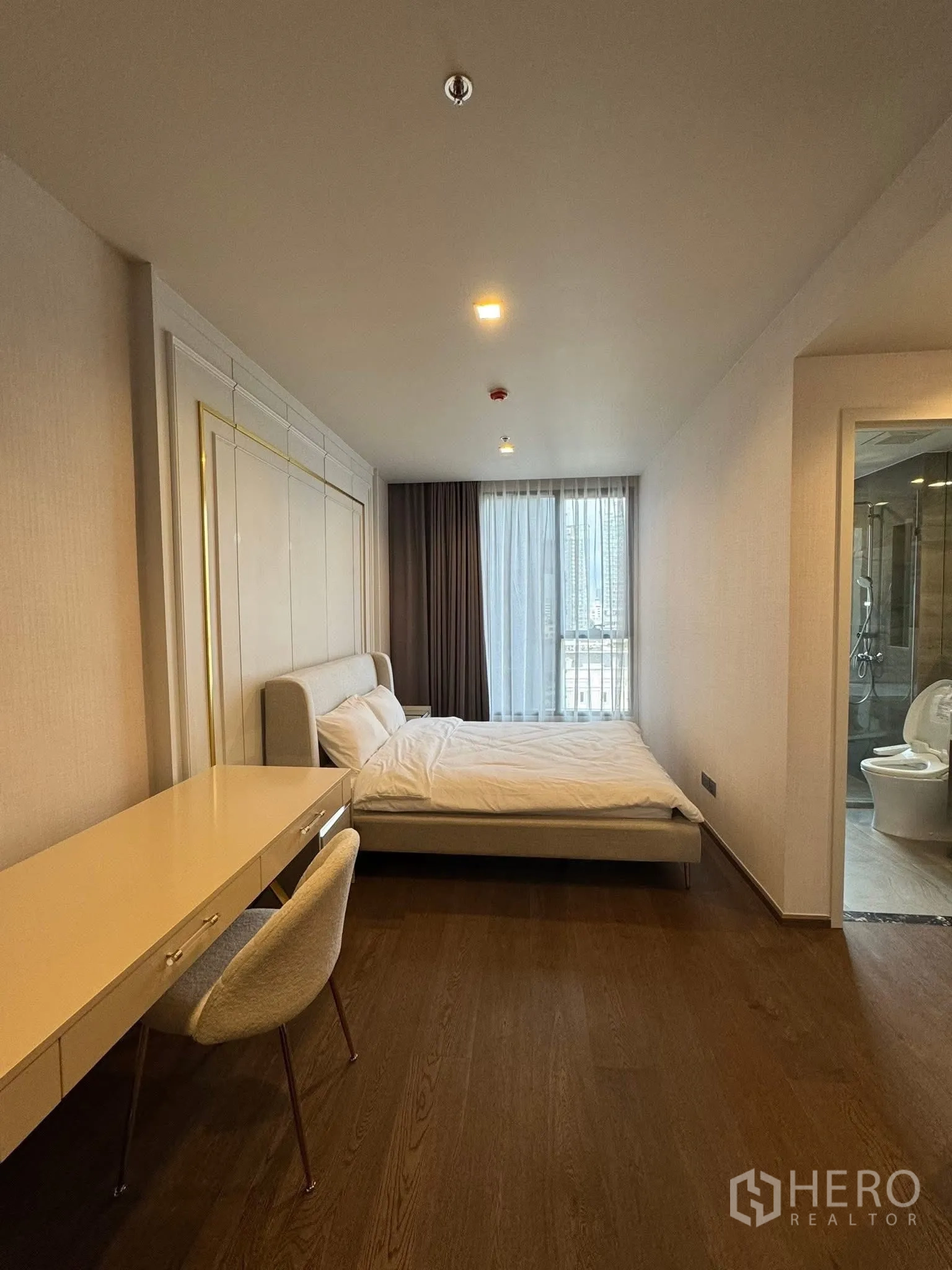 Condominium for rent in Khlong Toei, Bangkok - Spacious bedroom view toward the bathroom with wooden flooring.