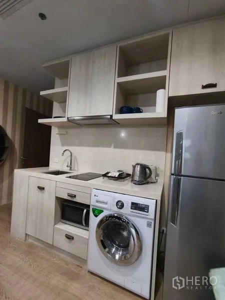 公寓 出租在Bangkok - 紧凑厨房配有水槽、电磁炉、微波炉、洗衣机与不锈钢冰箱。