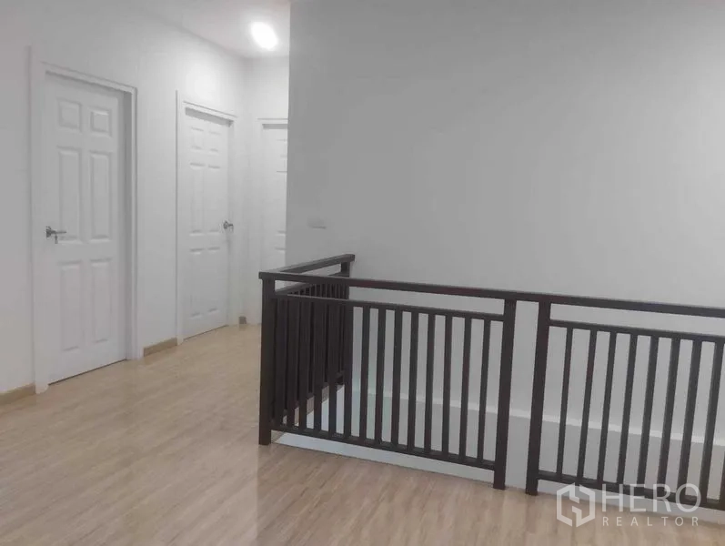 Detached House for sale in Phra Khanong, Bangkok - Upstairs landing with dark wood railing and multiple bedroom doors.