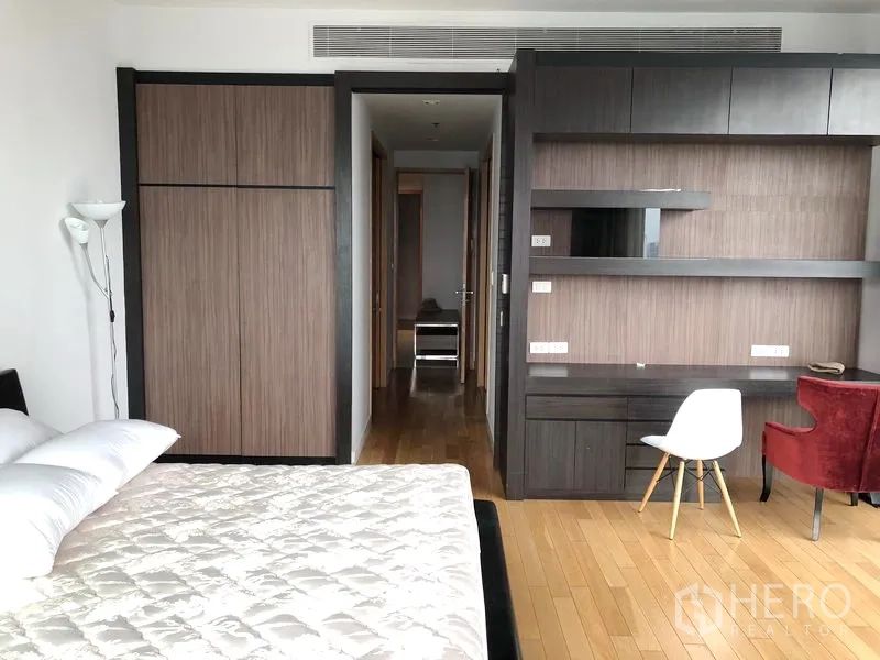 Condominium for rent in Khlong Toei, Bangkok - Primary bedroom with wood flooring, built-in wardrobe, desk, and shelving.