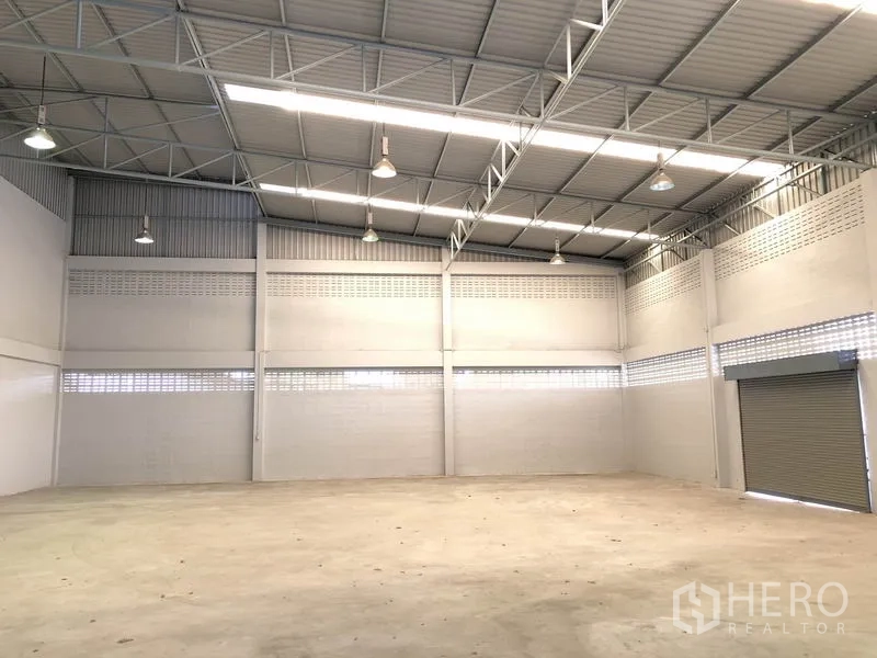 Factory for rent in Lat Lum Kaeo, Pathum Thani - Open warehouse space with smooth concrete floor and loading shutters