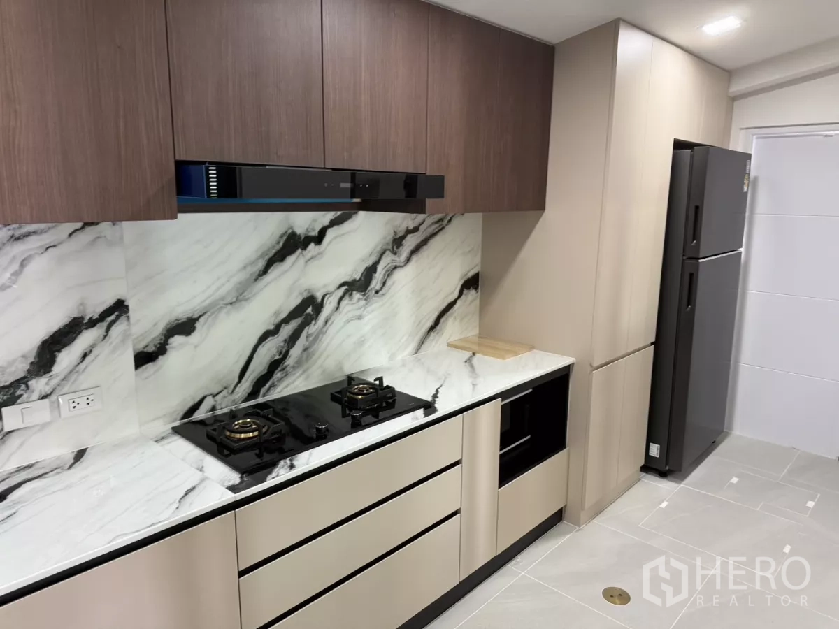 Townhouse for rent or sale in Bang Phli, Samut Prakan - Modern kitchen with marble backsplash, gas hobs, oven and tall cabinets.