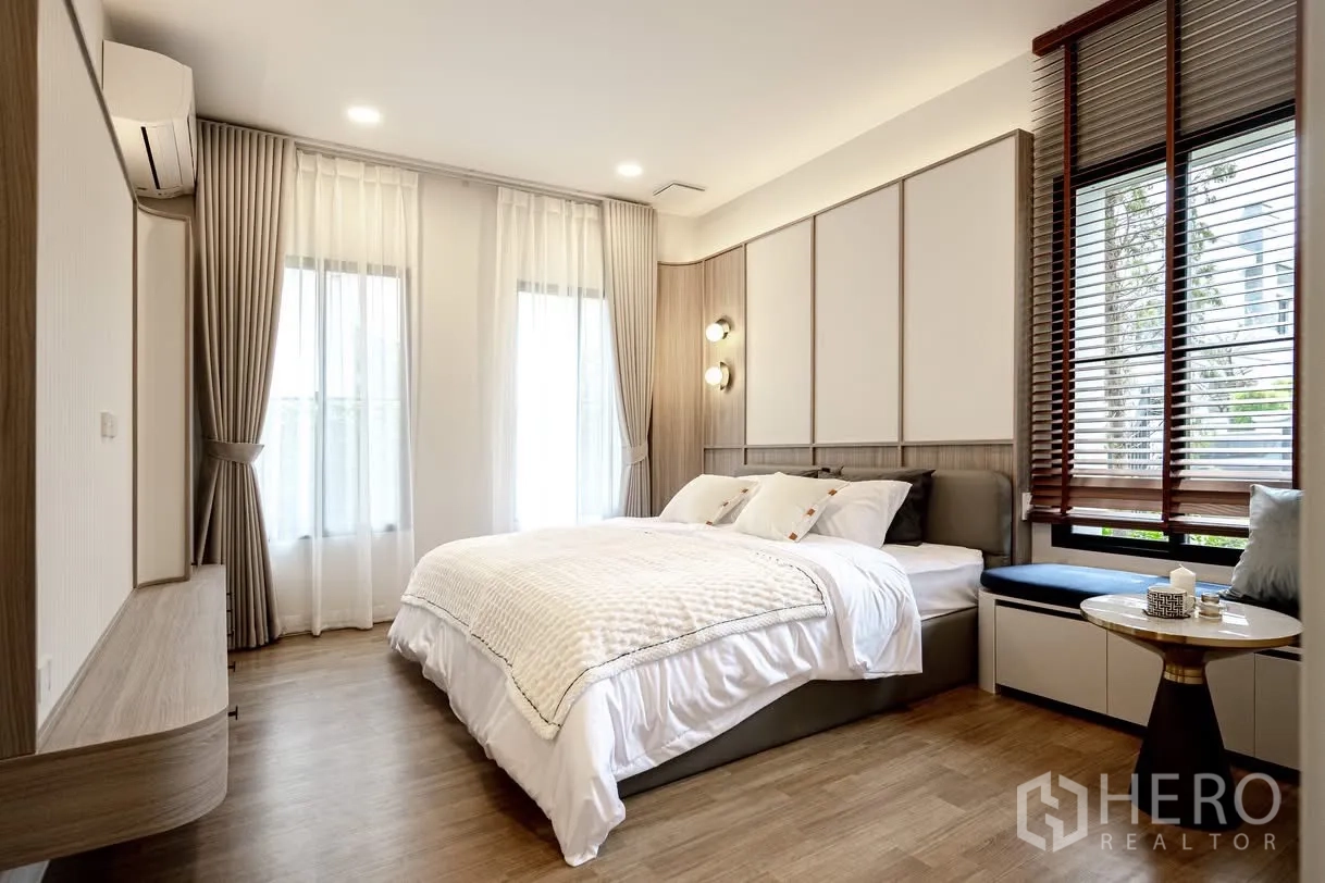 Detached House for rent in Saphan Sung, Bangkok - Cozy bedroom with wood floors, bay window seat, layered curtains, and wall sconces.