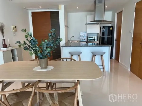 公寓 出租在Watthana, Bangkok - 现代用餐区，毗邻带中岛和不锈钢烟机的装修厨房。