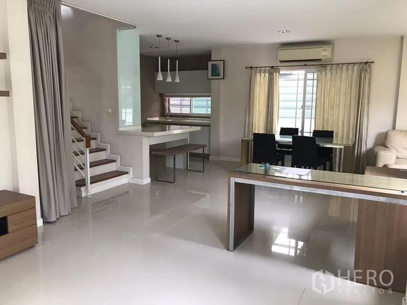 独立式住宅 出租在Khlong Sam Wa, Bangkok - 一层开放式客餐厅与楼梯，亮面地砖与用餐吧台。