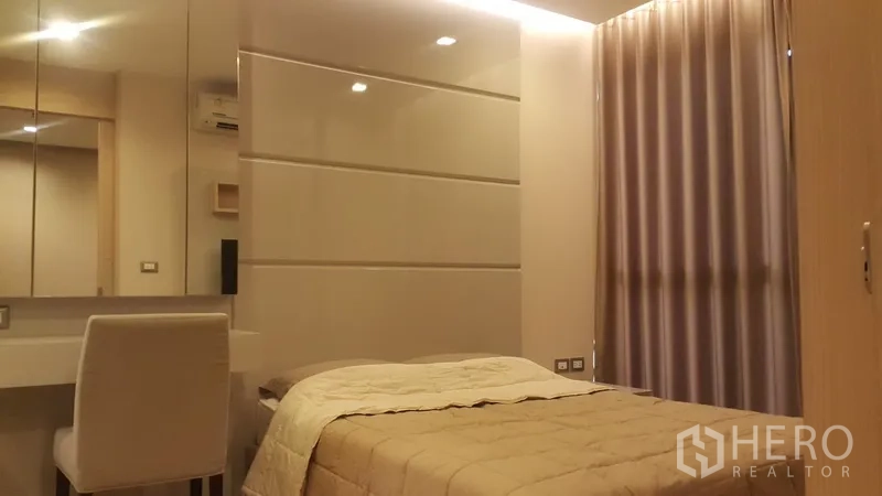 公寓 出租在Ratchathewi, Bangkok - 温馨卧室，内置梳妆台、镜面墙板与落地窗帘。