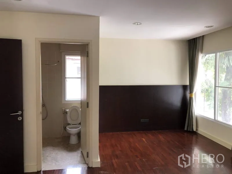 Detached House for sale in Wang Thonglang, Bangkok - Second bedroom with en-suite access, wood floors, and a large window with garden view.
