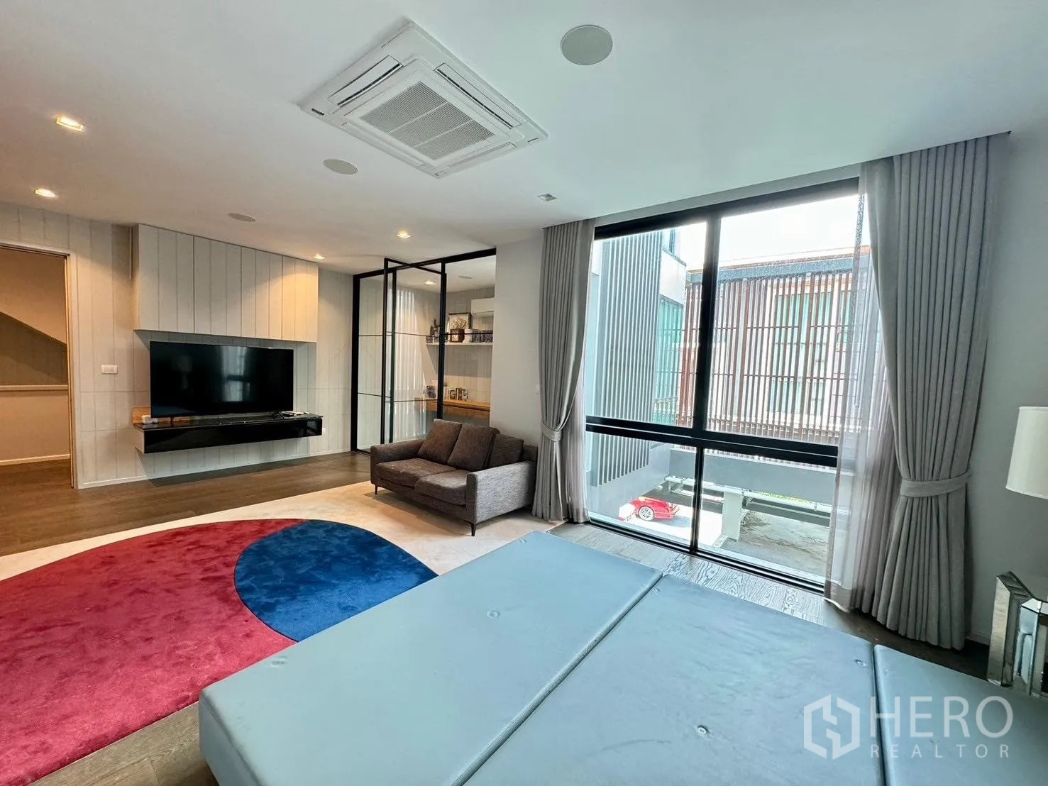 独立式住宅 出租或出售在Prawet, Bangkok - 家庭客厅，落地窗与窗帘，墙面悬挂电视。