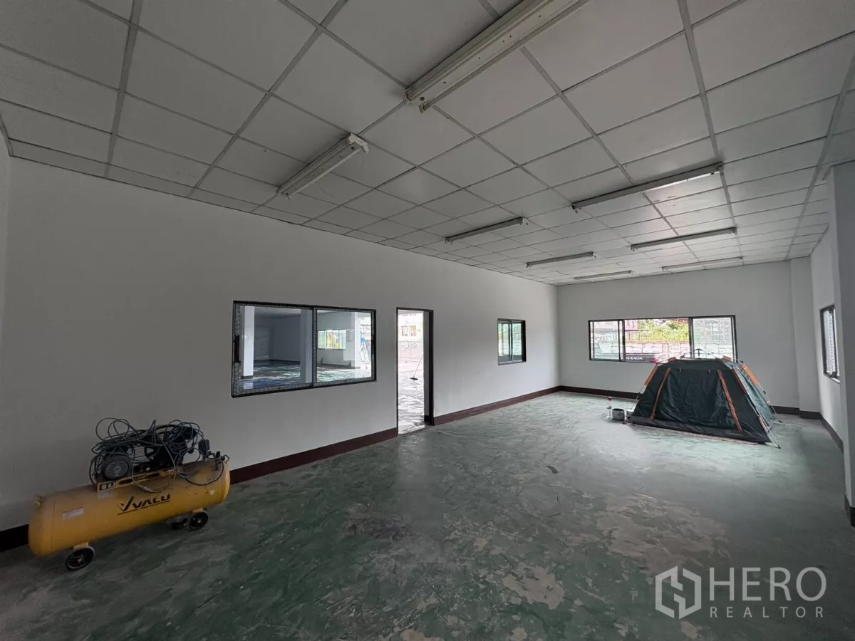 Factory for rent in Khlong Toei, Bangkok - Office room with grid ceiling, windows and unfinished concrete floor ready for fit-out.