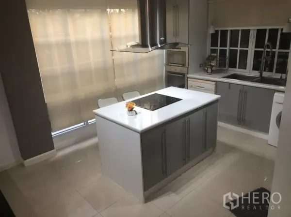 Townhouse for rent in Bang Kapi, Bangkok - Modern kitchen featuring a white island, induction hob, built-in oven and ample storage.