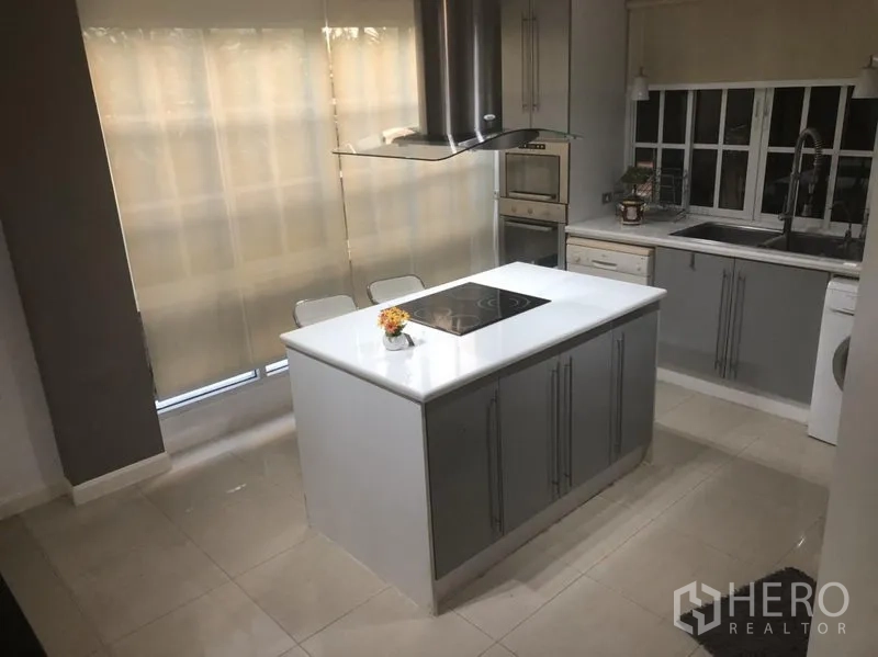 Townhouse for rent in Bang Kapi, Bangkok - Modern kitchen featuring a white island, induction hob, built-in oven and ample storage.