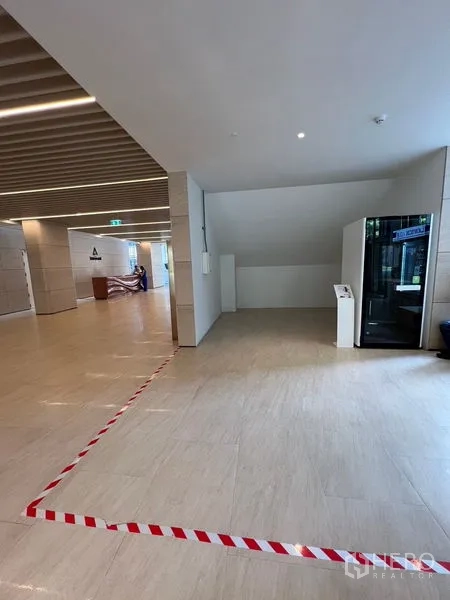Retail Space for rent - Corner retail space under a staircase within a contemporary lobby with wood‑slat ceiling.