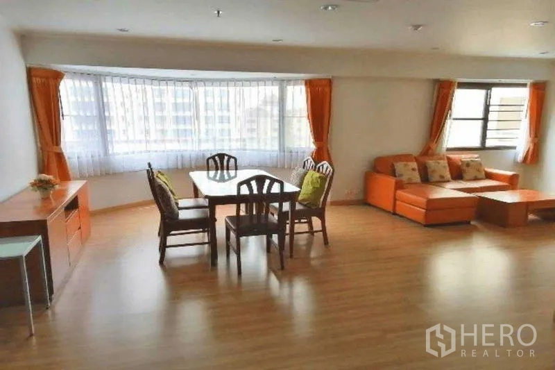 公寓 出租在Watthana, Bangkok - 明亮的客餐厅一体空间，带飘窗、橙色窗帘与木地板。