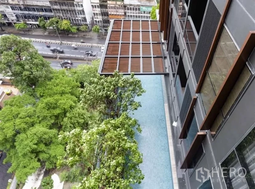 公寓 出租在Ratchathewi, Bangkok - 高楼层俯瞰泳池景观，下方绿树与城市街景相伴。
