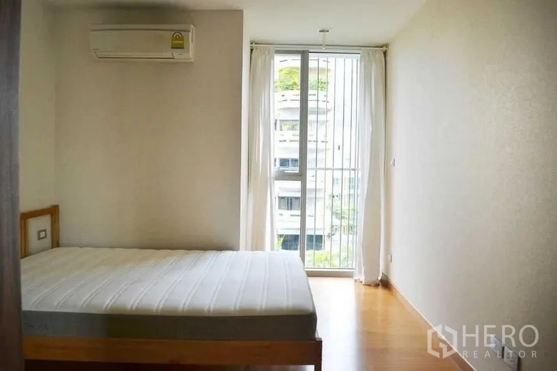 公寓 出租在Watthana, Bangkok - 明亮卧室，配床、空调与落地推拉门通向小阳台。