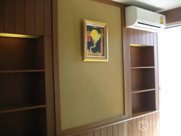 公寓 出租在Khlong Toei, Bangkok - 卧室墙面设有嵌入式书架与空调，挂画点缀，邻近采光窗。