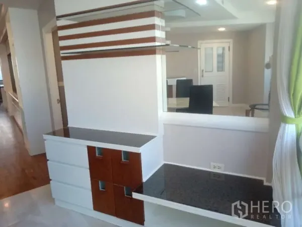 Condominium for rent in Khlong Toei, Bangkok - Living area divider with built‑in shelves and striped wall panels for extra storage.