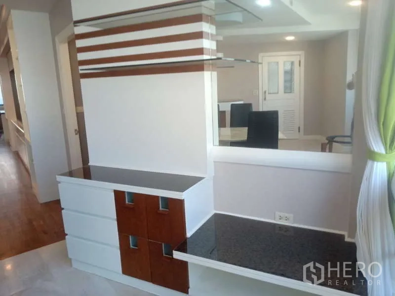 Condominium for rent in Khlong Toei, Bangkok - Living area divider with built‑in shelves and striped wall panels for extra storage.