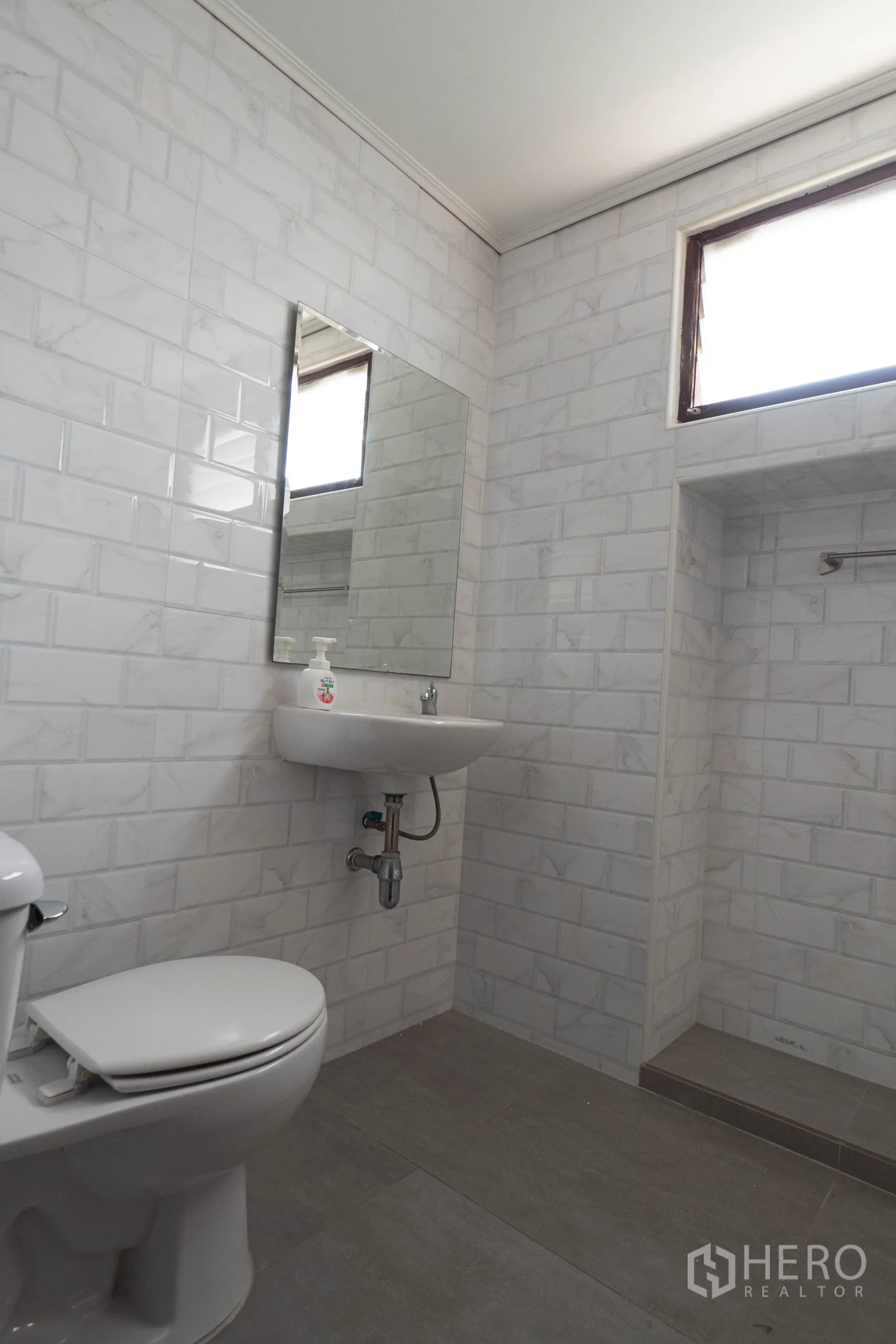 Townhouse for rent in Khlong Toei, Bangkok - Bathroom with white subway tiles, mirror, toilet and a step-in shower alcove.