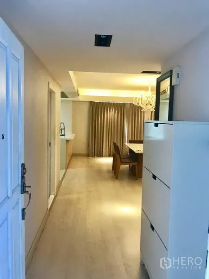 Condominium for rent in Watthana, Bangkok - Bright entry corridor leading to an open-plan dining area with light wood floors and full-length curtains.