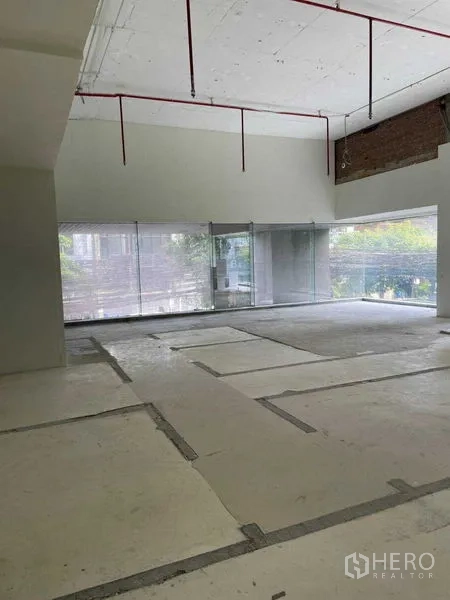 办公空间 出租在Watthana, Bangkok - 高挑层高的办公楼层，外露喷淋管与整面玻璃窗。