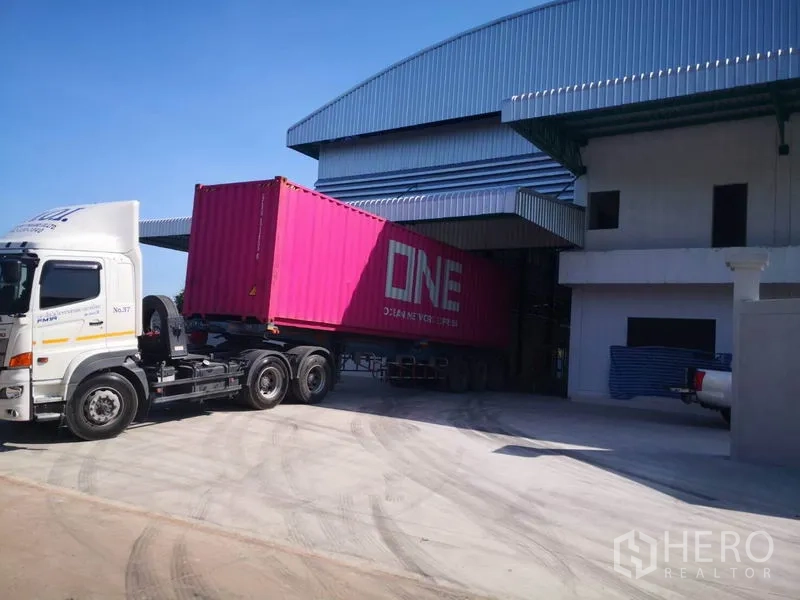 Factory for rent or sale in Mueang Samut Sakhon, Samut Sakhon - Container truck loading at the factory’s covered dock and wide driveway.