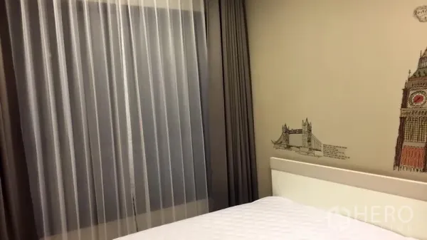 Condominium for sale in Huai Khwang, Bangkok - Bright bedroom with large window, sheer and blackout curtains, and decorative wall art.