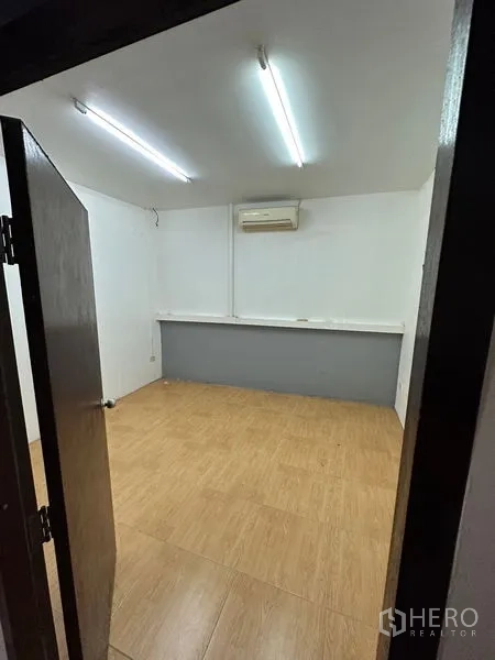 Townhouse for rent in Bang Kapi, Bangkok - Multipurpose room with wood-look floor, fluorescent lights and wall air-conditioner.