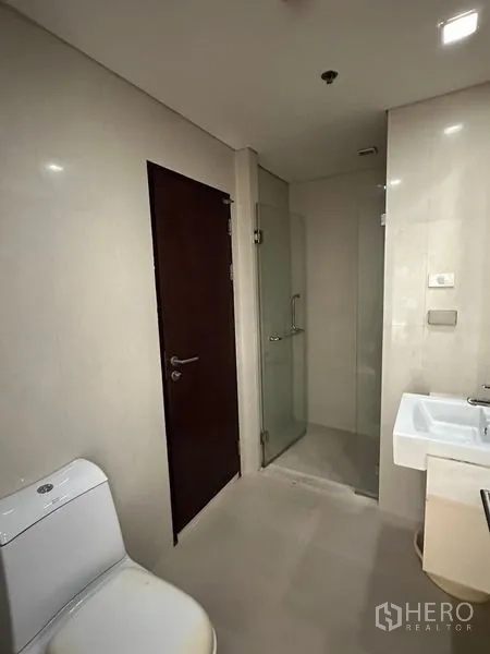 公寓 出售在Watthana, Bangkok - 现代浴室，马桶、台盆与玻璃淋浴间。