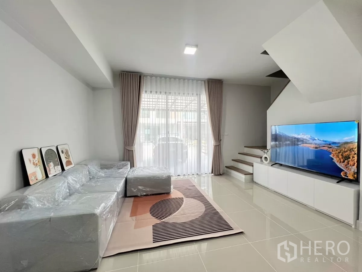 联排别墅 出租在Bang Phli, Samut Prakan - 明亮客厅，配大沙发、电视柜与楼梯