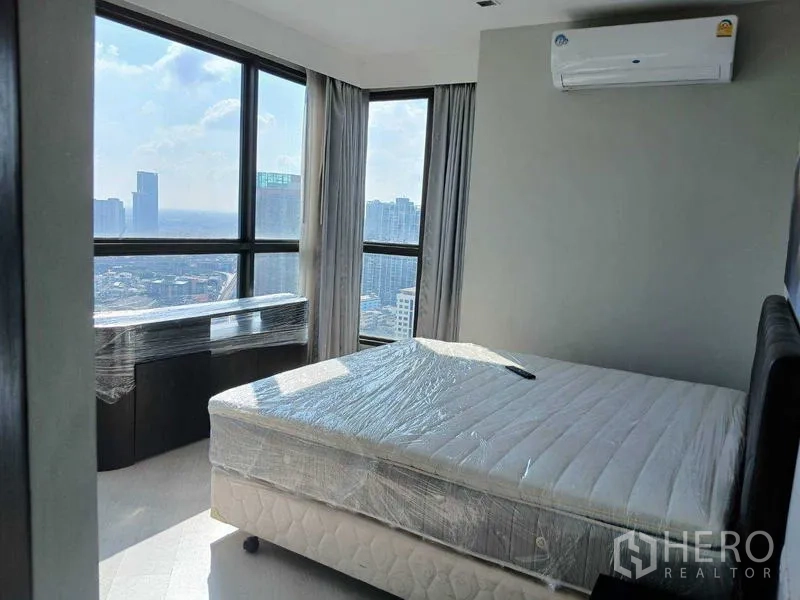 Condominium for rent - Master bedroom with corner floor-to-ceiling windows, double bed and skyline outlook.