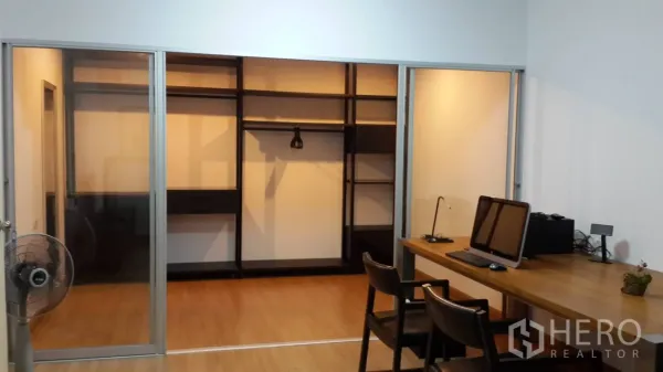 公寓 出租在Huai Khwang, Bangkok - 推拉玻璃门通向带层架的步入式衣帽间，旁有家用办公桌