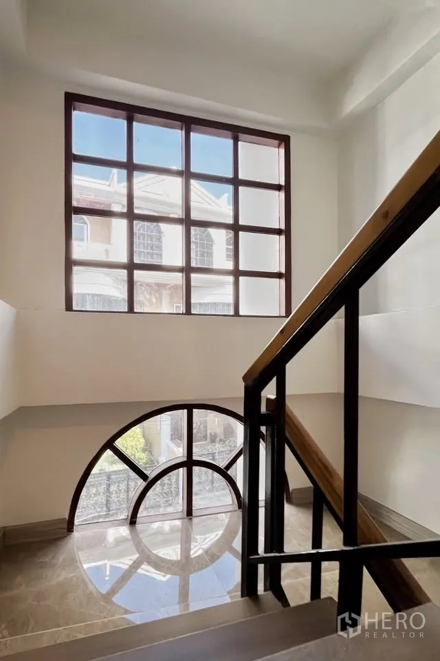 带办公室的家 出租在Watthana, Bangkok - 楼梯间，木金属扶手与拱形及格栅大窗。
